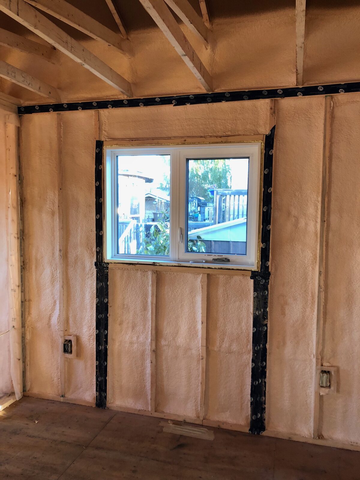 Small bedroom wall with a window, foamed stud bays and taped jambs and top plate