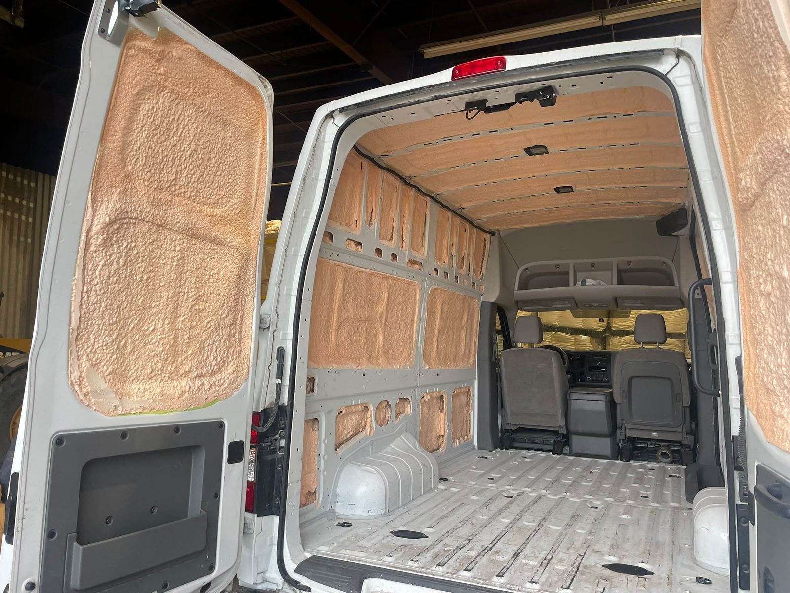 Cargo van interior with closed-cell spray foam fully applied to the ceiling ribs, side walls and rear doors