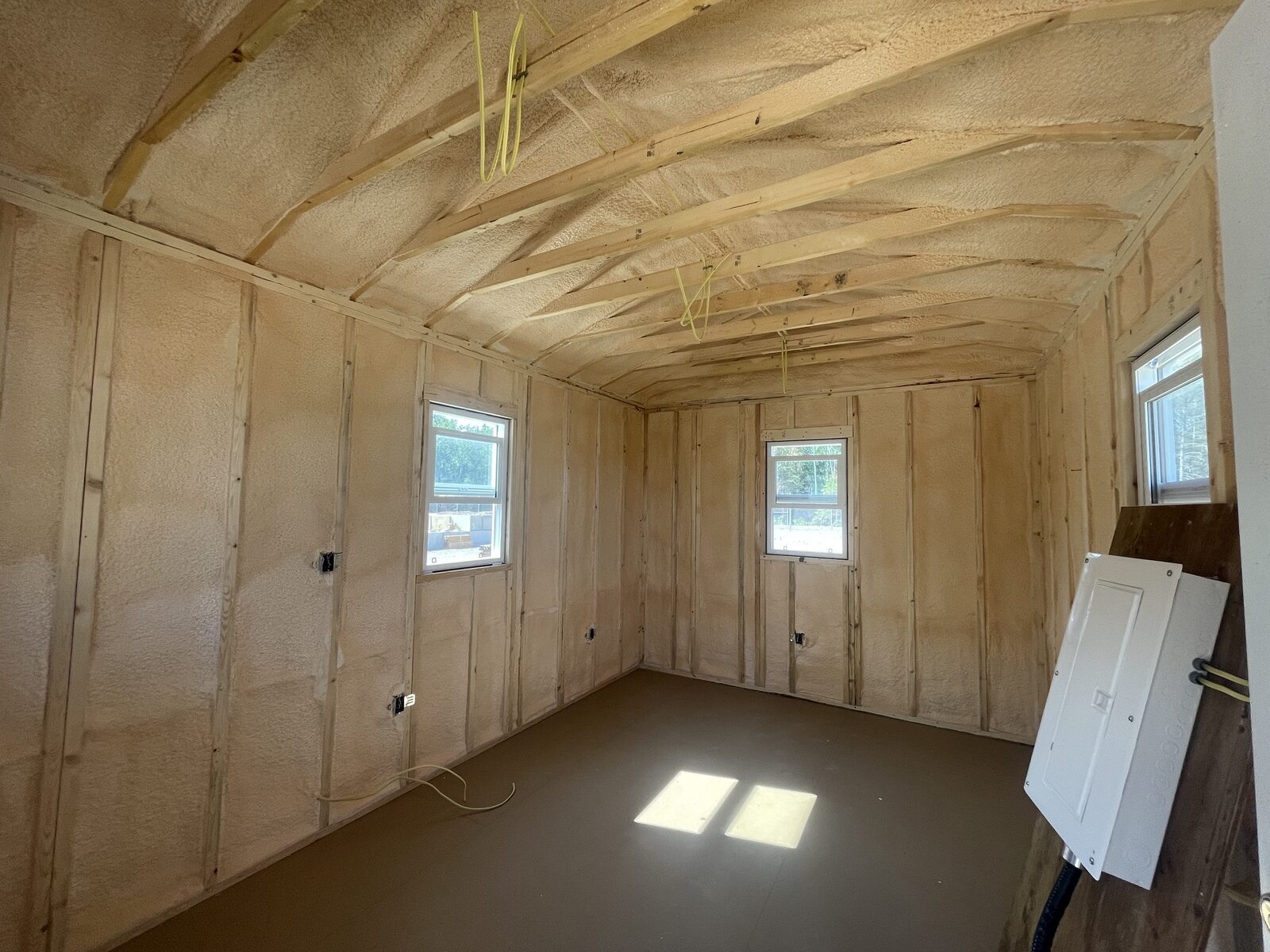 Interior of the Victoria Beach staff bunkie with closed-cell spray foam on the walls and low vaulted ceiling, electrical panel roughed in
